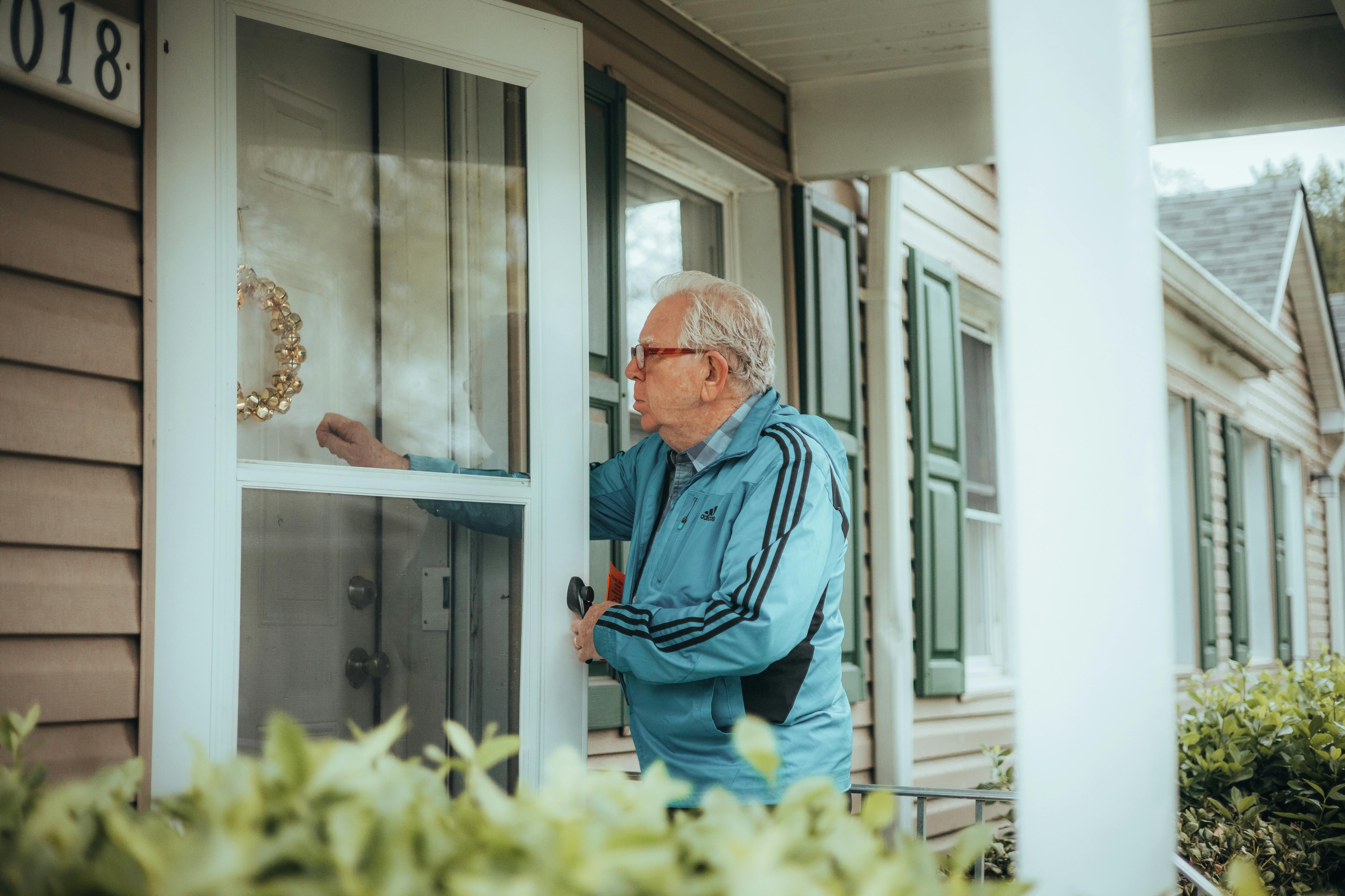 Un homme âgé frappant à une porte.