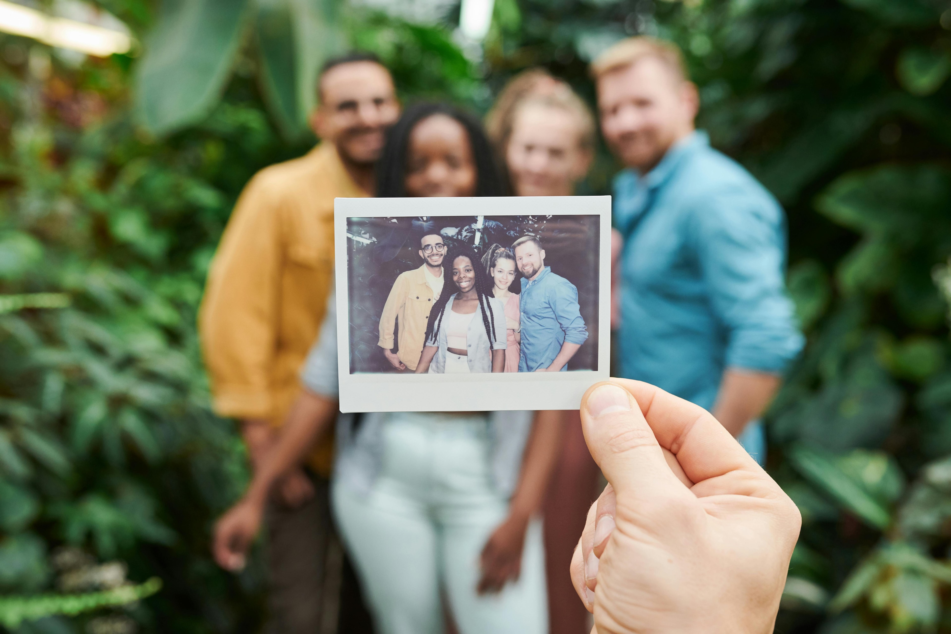 Une main tenant une photo devant les mêmes personnes